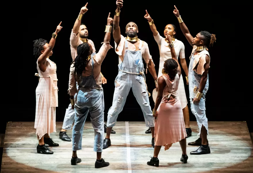 StepAfrika dancers stand in a circle pointing up.