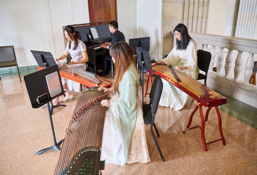 Four musicians one playing the piano and three playing Asian string instruments.