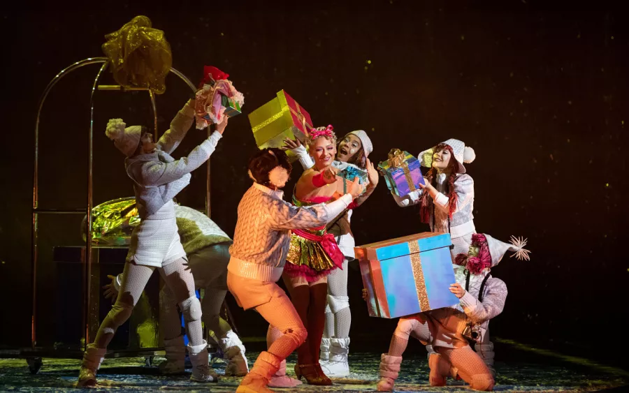 Performers handling large gift boxes from a hotel luggage cart