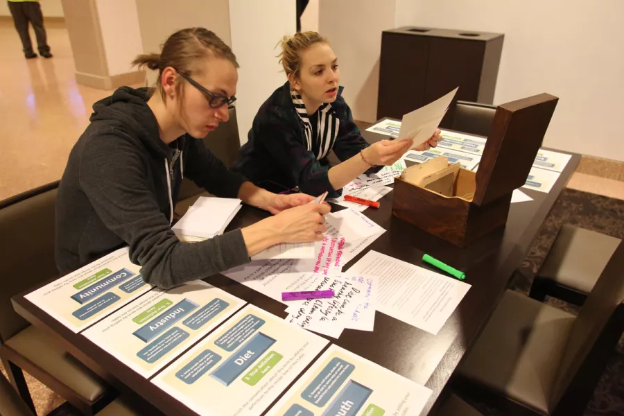 Two people working with papers at a table in a student lounge.