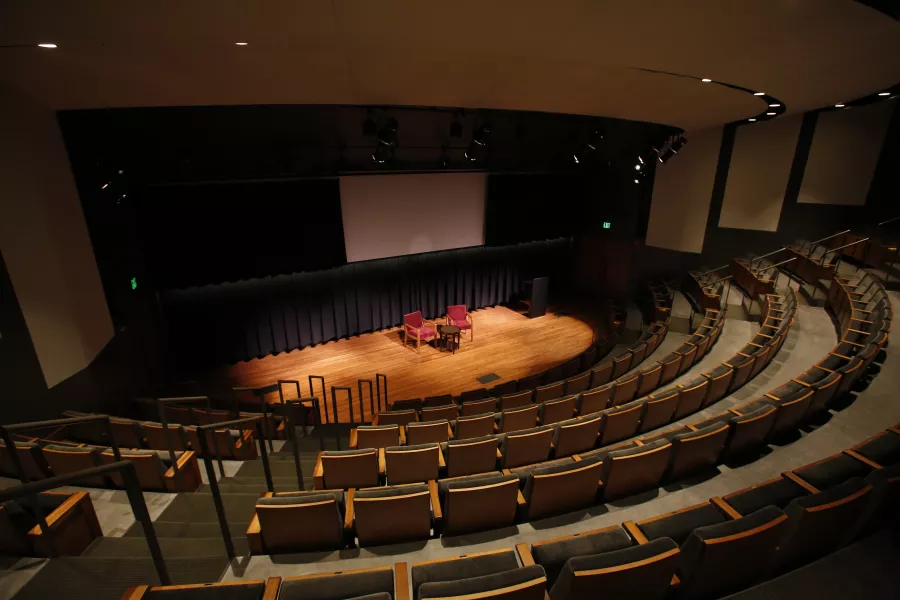 The seats and stage in the Best Buy Theater taken from high up. There are two empty chairs on the stage.