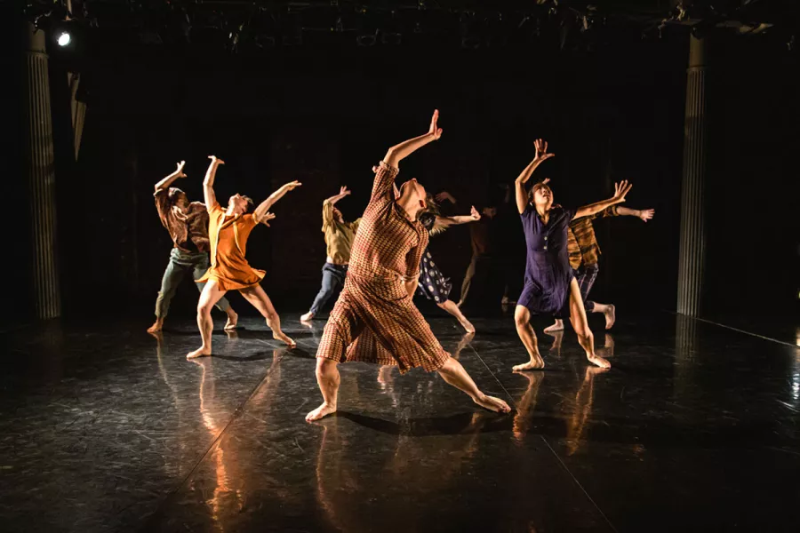Three male Gallim dancers perform on stage with a black background.
