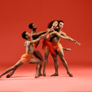 Four Dance Theatre of Harlem dancers perform together in front of an orange background.